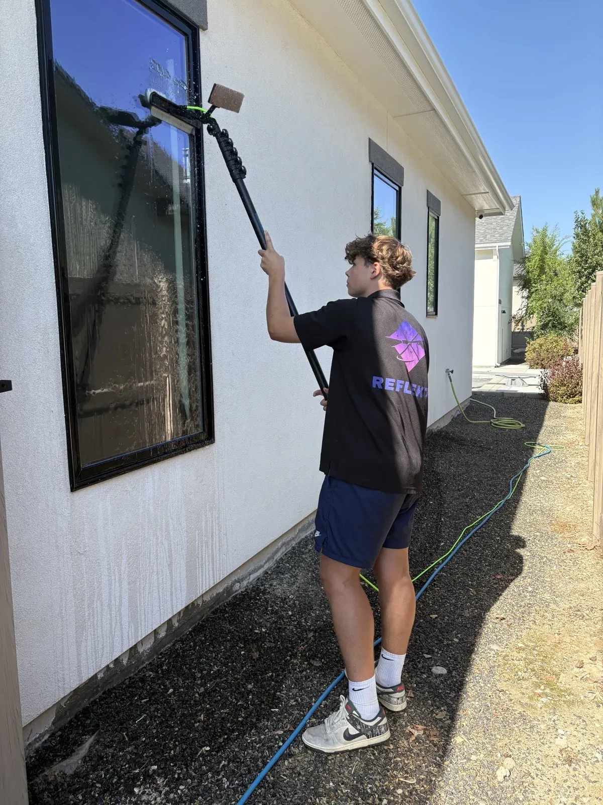 Reflekt technician cleaning exterior windows with a water-fed pole in the Treasure Valley, Idaho