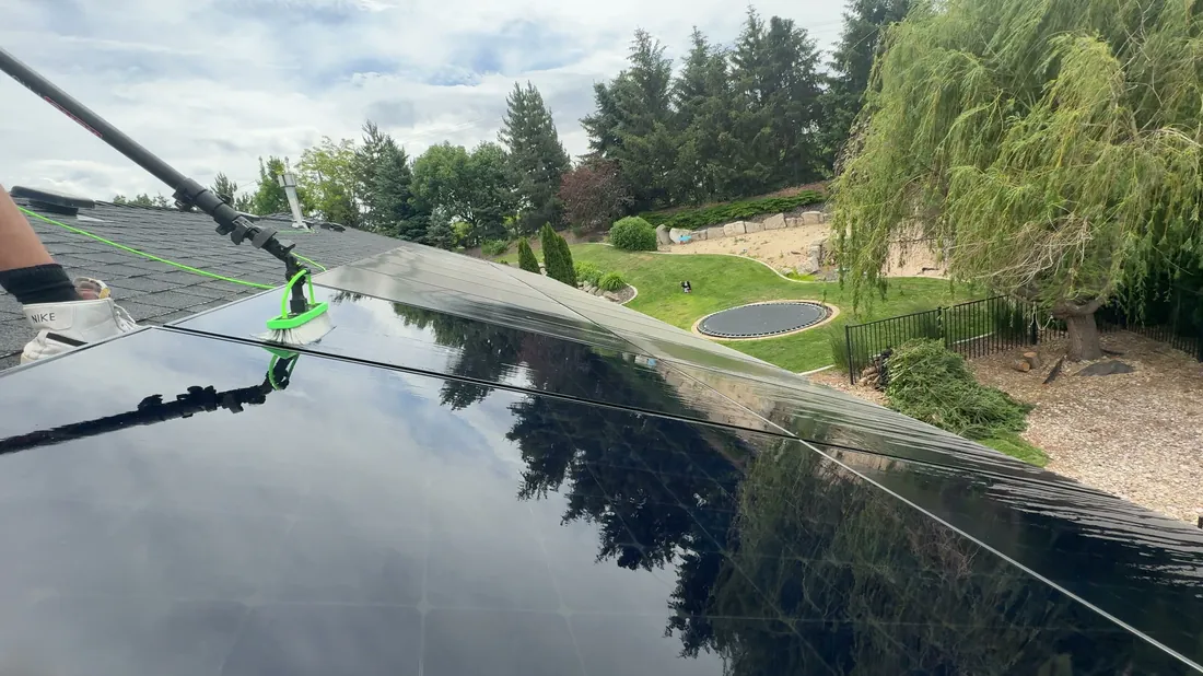 Reflekt crew washing a rooftop solar panel with a soft brush in the Treasure Valley, Idaho
